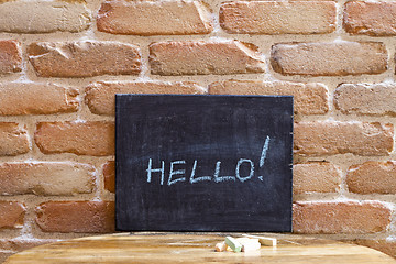 Image showing Black board with the word HELLO! drown by hand on wooden table o