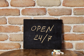 Image showing Black chalkboard with the phrase OPEN 24/7 drown by hand on wood