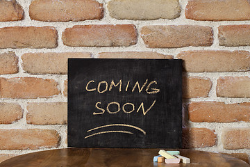 Image showing Black board with the phrase COMING SOON drown by hand on wooden 