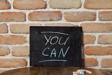 Image showing Black board with the phrase YOU CAN drown by hand on wooden tabl