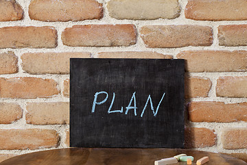 Image showing Chalk board with the word PLAN drown by hand on wooden table on 