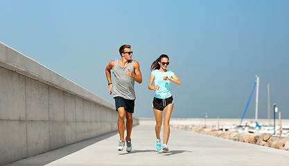 Image showing couple with fitness tracker running along pier