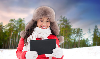 Image showing woman in fur hat with tablet pc over winter forest