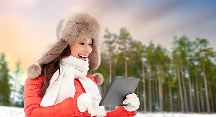 Image showing woman in fur hat with tablet pc over winter forest