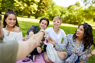 Image showing happy friends clinking drinks at summer park