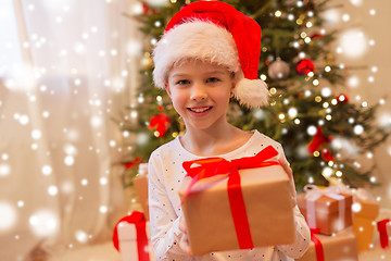 Image showing smiling girl in santa hat with christmas gift