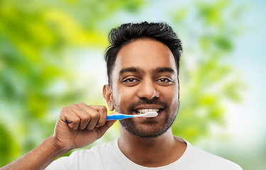 Image showing indian man cleaning teeth over natural background