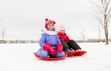 Image showing happy little girls on sleds outdoors in winter