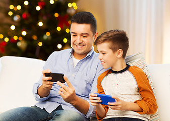 Image showing happy father and son with smartphones on christmas