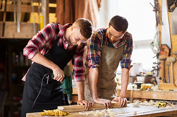 Image showing carpenters with drill drilling board at workshop