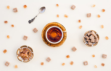 Image showing Cup of tea and brown sugar on white background