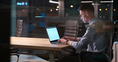 Image showing man working on laptop in dark office