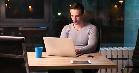 Image showing man working on laptop in dark office