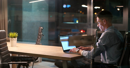 Image showing man working on laptop in dark office