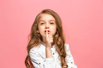 Image showing The young teen girl whispering a secret behind her hand over pink background