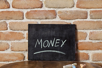 Image showing Chalk board with the word MONEY drown by hand on wooden table on