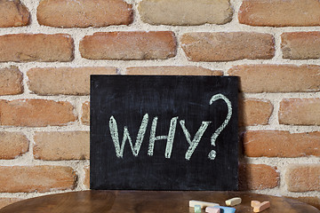 Image showing Black board with the word WHY? drown by hand on wooden table on 