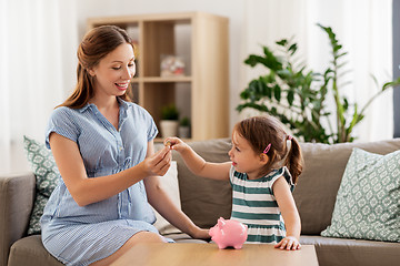 Image showing pregnant mother and daughter with piggy bank