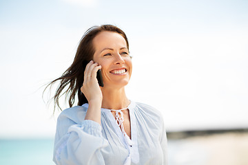 Image showing happy woman calling on smartphone on summer beach