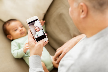 Image showing father photographing baby by smartphone