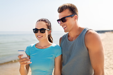 Image showing couple in sports clothes with smartphones on beach