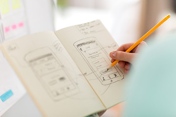 Image showing ui designer with user interface sketch in notebook