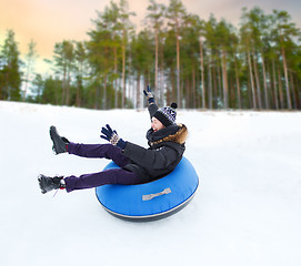 Image showing happy young man sliding down hill on snow tube