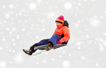 Image showing happy little girl sliding down on sled in winter