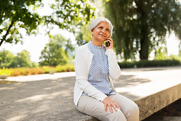 Image showing happy senior woman calling on smartphone in summer