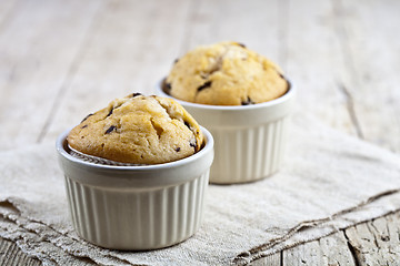 Image showing Homemade fresh muffins on ceramic white bowls on linen napkin.