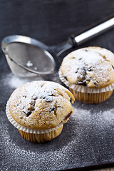 Image showing Two fresh homemade muffins with sugar powder and metal strainer 