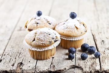 Image showing Homemade fresh muffins with blueberries on rustic wooden table.