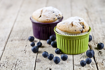 Image showing Two homemade fresh muffins on ceramic green and purple bowls wit