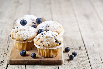 Image showing Four homemade fresh muffins with blueberries on rustic wooden ta