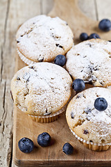 Image showing Four homemade fresh muffins with blueberries on rustic wooden ta