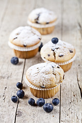 Image showing Four fresh homemade muffins with blueberries on rustic wooden ta