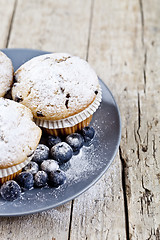 Image showing Homemade fresh muffins with sugar powder and blueberries on cera