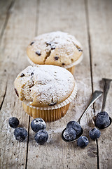 Image showing Two homemade fresh muffins with sugar powder, vintage spoons and