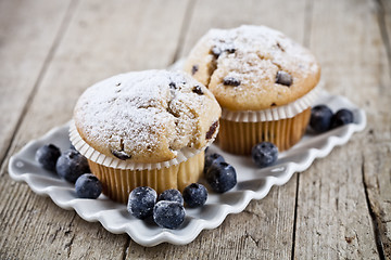 Image showing Homemade fresh muffins with sugar powder and blueberries on cera