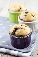 Image showing Three homemade fresh muffins on colorful ceramic bowls on linen 