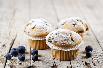 Image showing Three fresh baked homemade muffins with blueberries on rustic wo