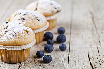 Image showing Three fresh baked homemade muffins with blueberries on rustic wo