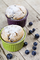 Image showing Two homemade fresh muffins on ceramic green and purple bowls wit