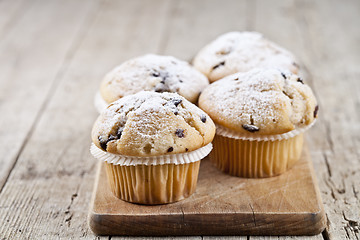 Image showing Four homemade fresh muffins with sugar powder and blueberries on