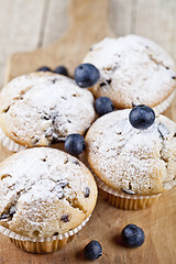 Image showing Four homemade fresh muffins with sugar powder and blueberries on