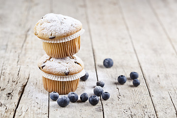 Image showing Two fresh homemade muffins with blueberries on rustic wooden tab