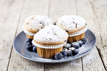 Image showing Three homemade fresh muffins with sugar powder and blueberries o