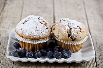 Image showing Homemade fresh muffins with sugar powder and blueberries on cera