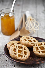 Image showing Fresh baked tarts with marmalade or apricot jam filling and on c