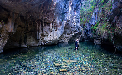 Image showing Female looks up in awe admiring the canyon walls and caves high 